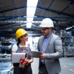 Manager supervisor and worker discussing about production results and new strategy in factory industrial hall.